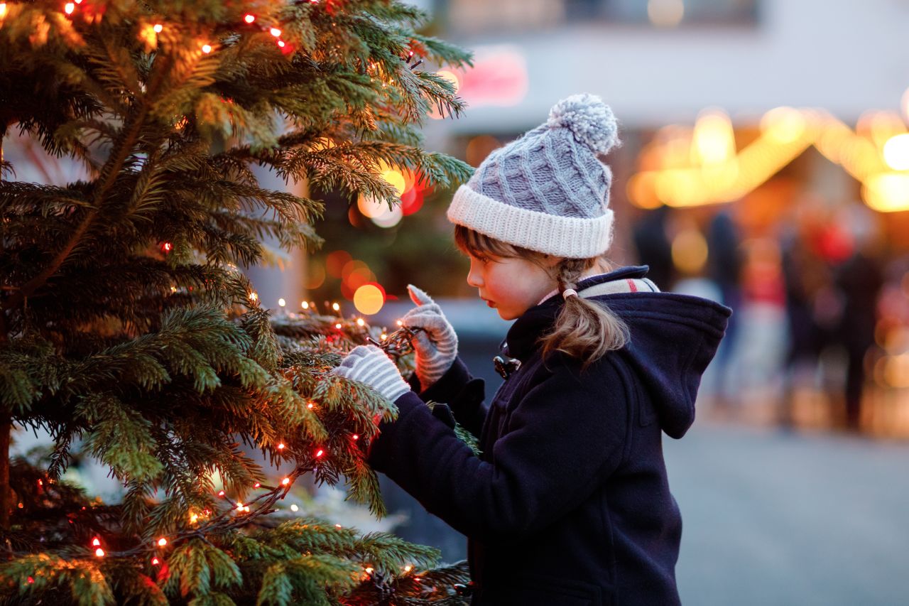 a little girl holding a candy cane at a Christmas market